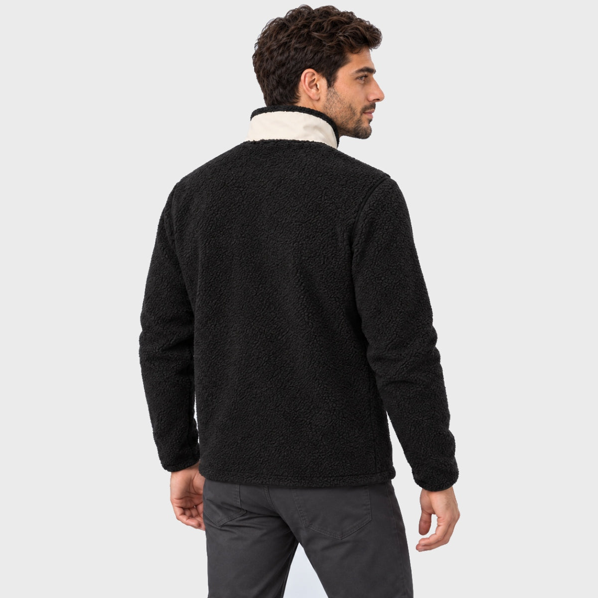 גבר לבוש במעיל Aztec Blizzard Sherpa Full Zip שחור, בעל שרוולים ארוכים, עם גימור מרקם וצווארון פנימי לבן.