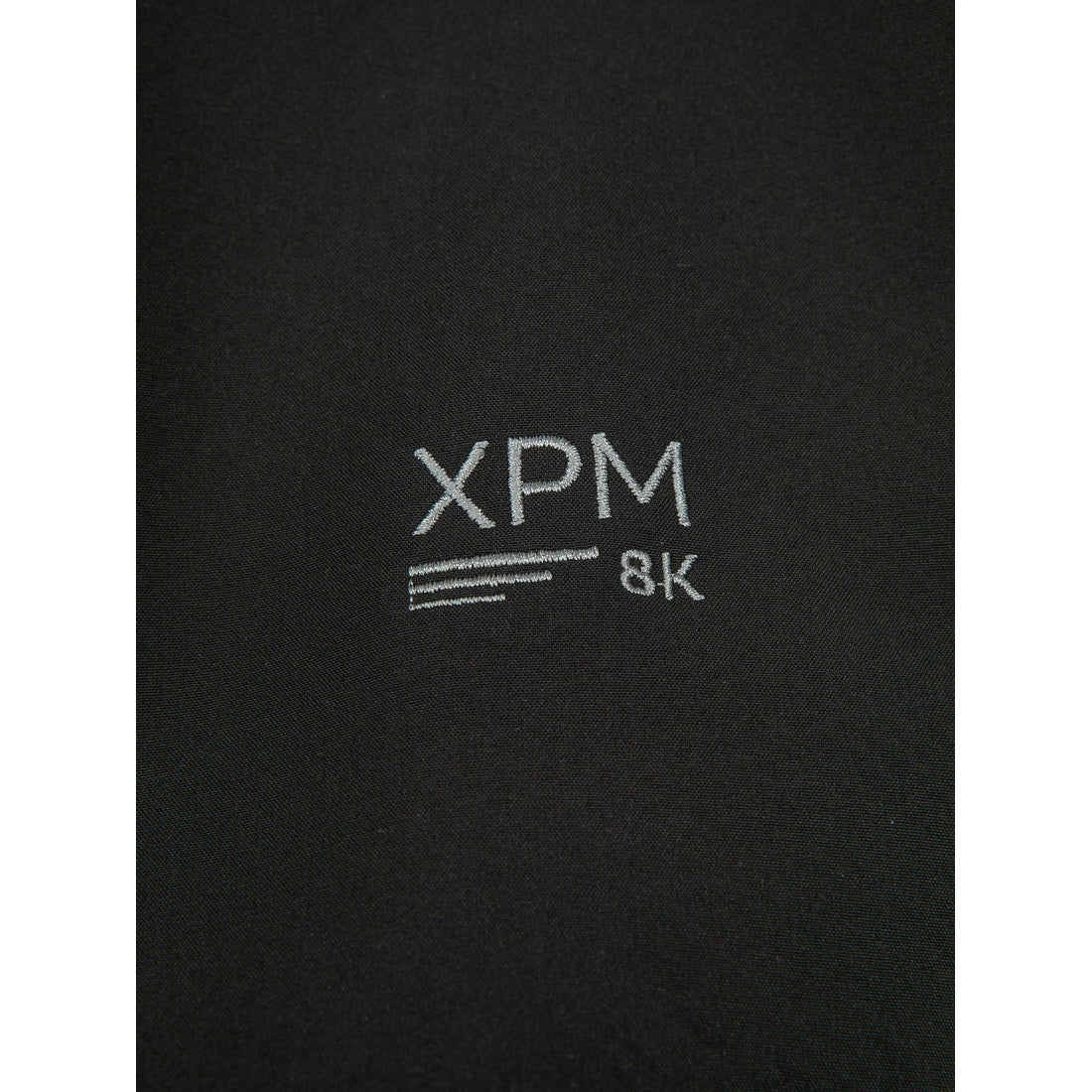 בד שחור עם הכיתוב "XPM 8K" ושלוש פסים לבנים אופקיים, רקומים בחוט לבן; בהשראת קולקציית Puffin X II של Aztec.
