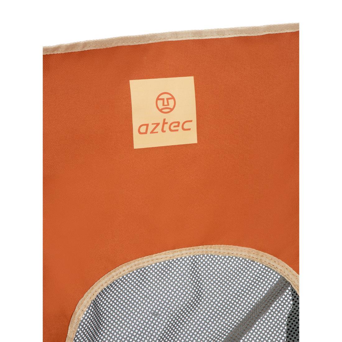 תקריב של הלוגו והשם "Aztec" על כיסא בד מדגם X3 של Moonox בצבע בז' בהיר/כתום, עם מושב כתום, תווית בצבע בז', קצה כיס מרשת, ושטיח MOONOX בצבע בז' בהיר הנראה מתחת.