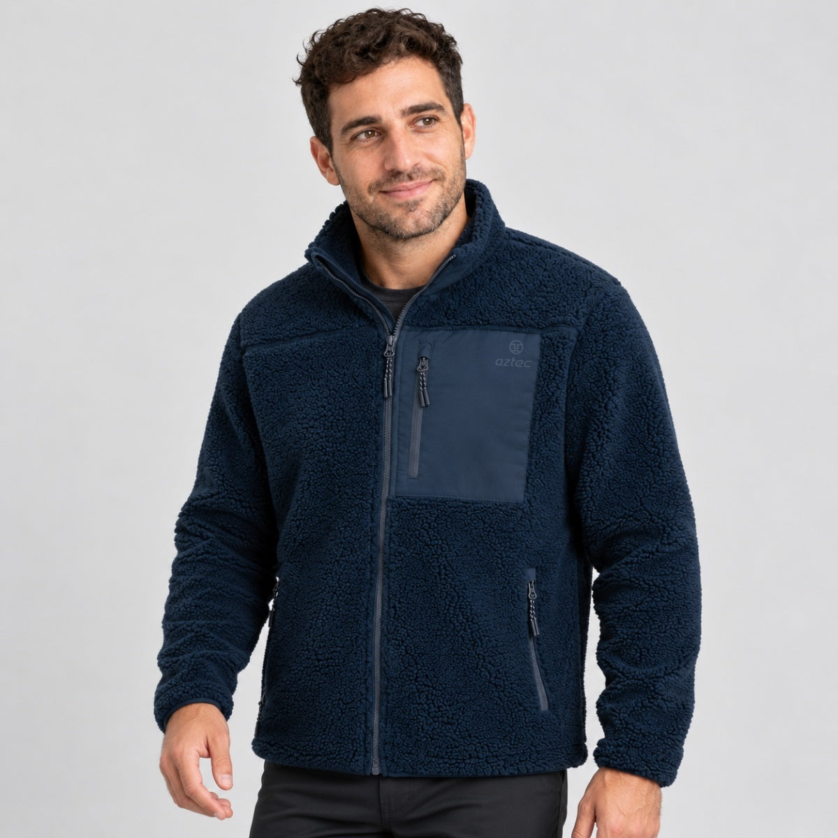 גבר לבוש במעיל Aztec Blizzard Sherpa Full Zip בצבע כחול כהה, עם רוכסן מלא, גימור מרקם וכיס חזה עם רוכסן.