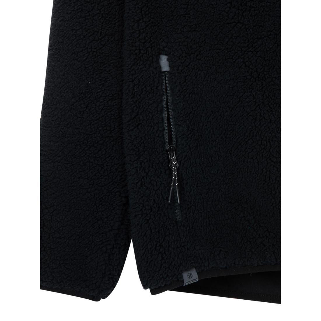 תקריב של מעיל ה-Aztec Blizzard Sherpa Full Zip Flag, המדגיש את הפליס המרקם שלו, את כיס הצדדי עם רוכסן ולשונית משיכה, ואת התווית הקטנה בקצה התחתון המוסיפה פרט מעניין.
