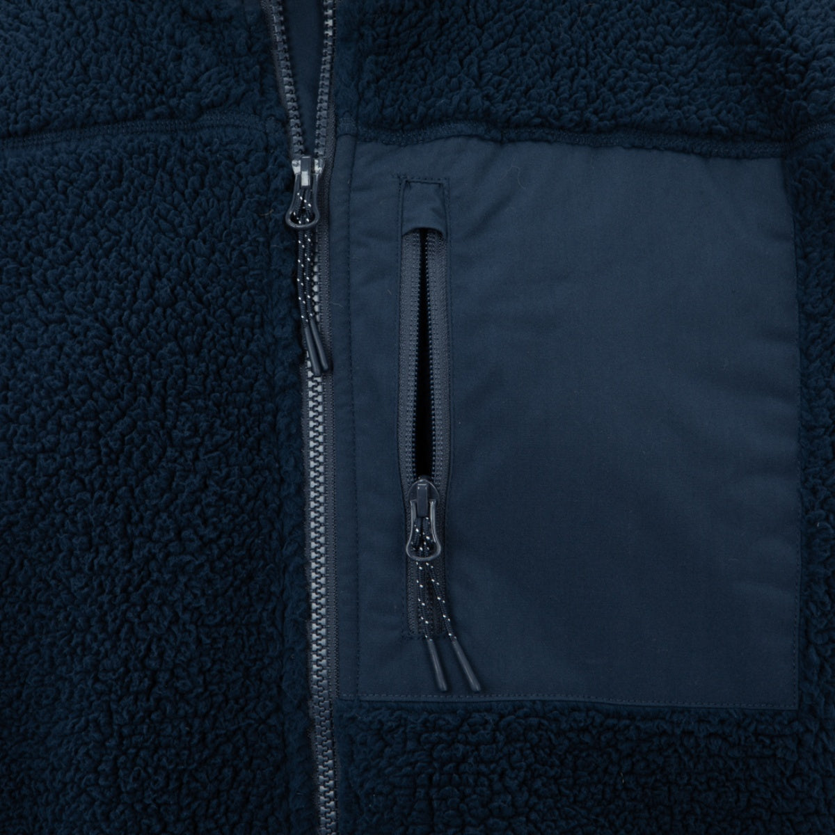 תקריב של מעיל שרפה Blizzard Sherpa Full Zip Flag בצבע כחול כהה ומרקם, הכולל רוכסן מרכזי וכיס חזה עם רוכסן ולוח חלק.