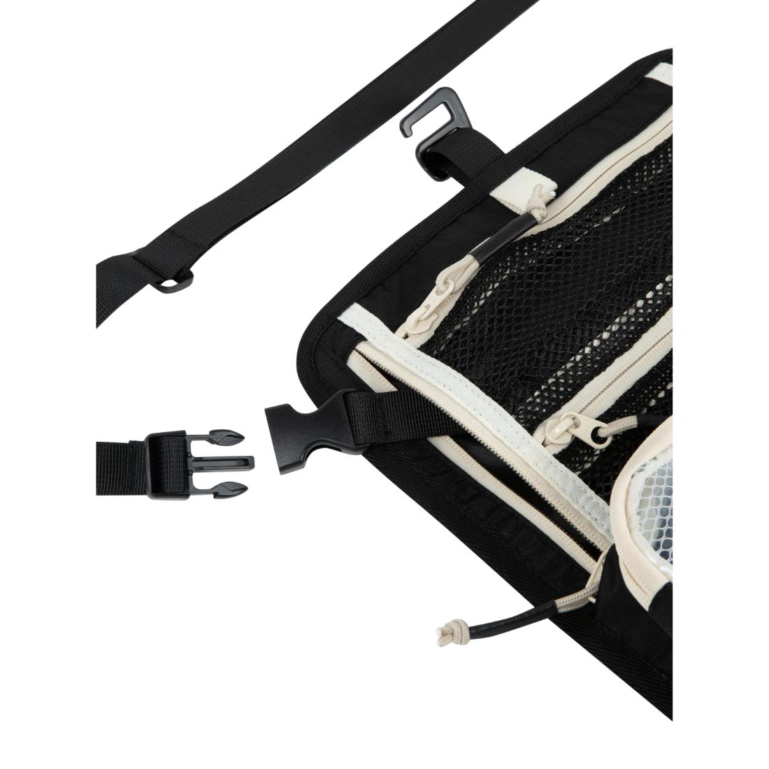 תקריב של תיק הארגון Aztec Vagabag בצבעים שחור וקרם, הכולל כיסים מרשת, רוכסנים ורצועות מתכווננות עם אבזמי פלסטיק, המוצג כשהוא פתוח חלקית על רקע לבן.