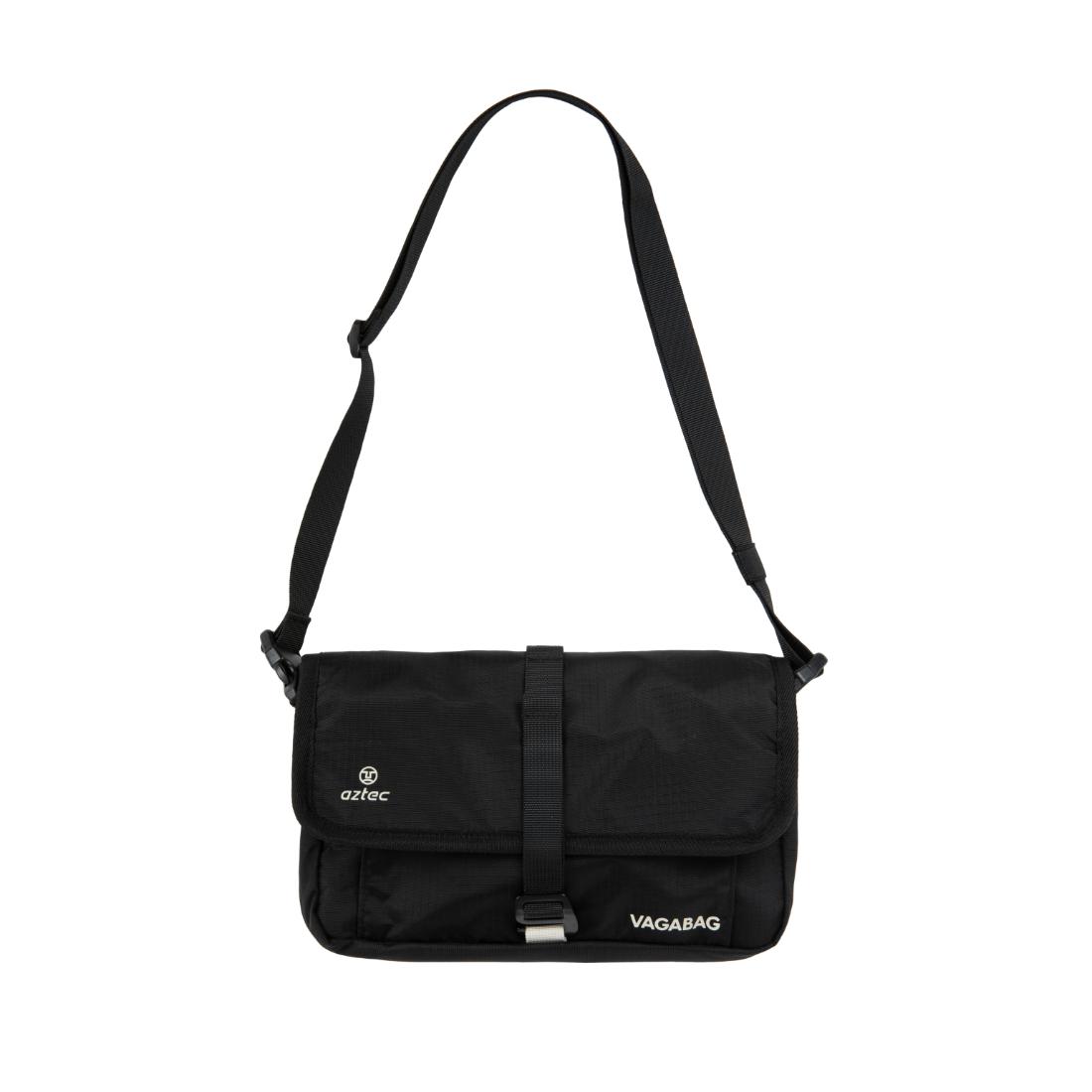 תיק כתף שחור ומלבני של Aztec Vagabag, עם רצועה מתכווננת, אבזם על הכיסוי הקדמי ושני לוגואים לבנים — Aztec משמאל, Vagabag מימין. העיצוב המינימליסטי שלו משתלב עם כל סגנון.