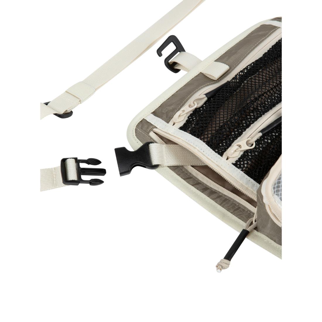 תקריב של תיק נסיעות Aztec Vagabag בצבעי בז' ושחור, עם כיסים מרשת, רוכסנים ורצועות מתכווננות עם אבזמי פלסטיק שחורים, המוצג ללא אבזמים ומונח שטוח על רקע לבן.