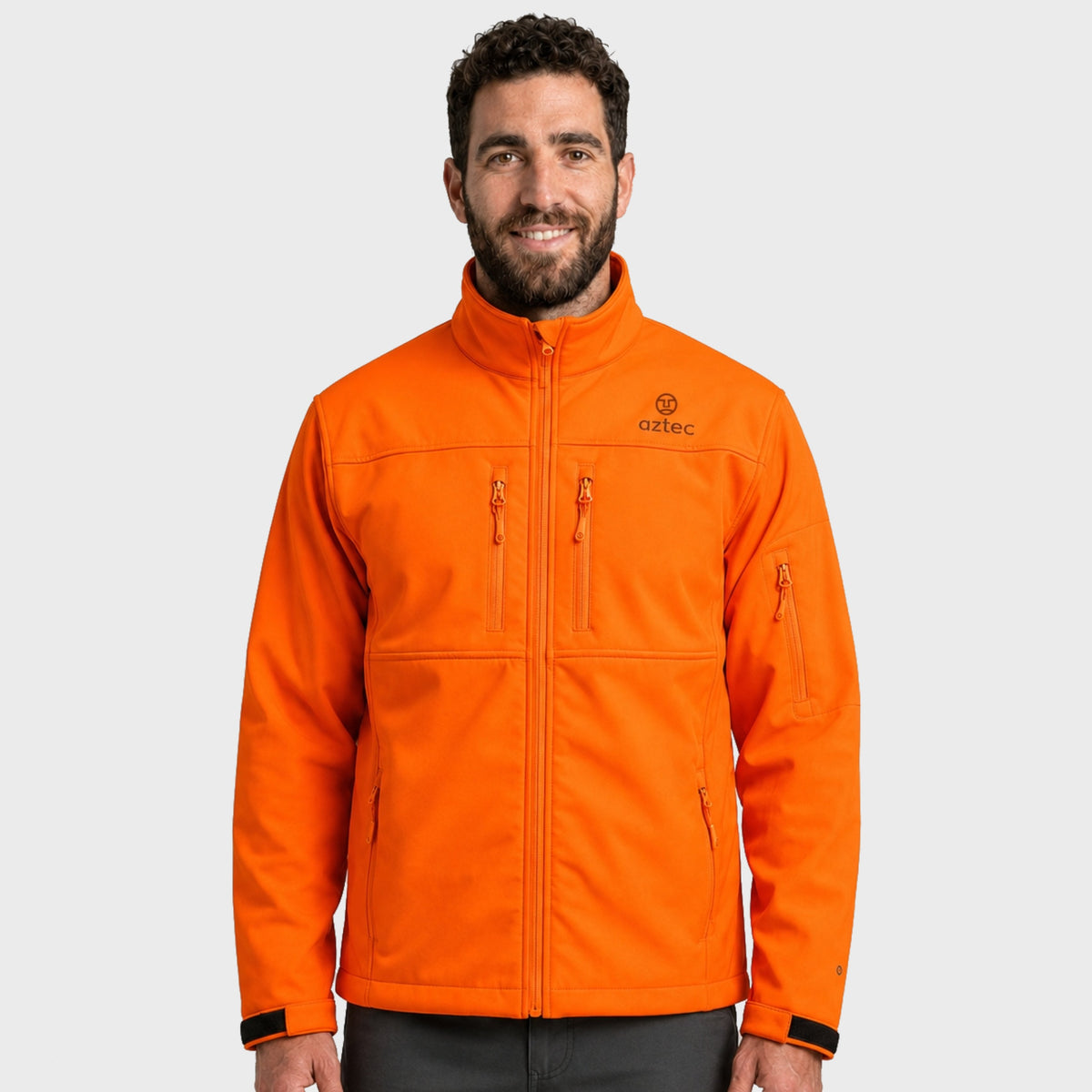 גבר מחייך הלובש מעיל Aztec Recovery Softshell בצבע כתום בוהק, עם כיס בחזה עם רוכסן וצווארון עומד.