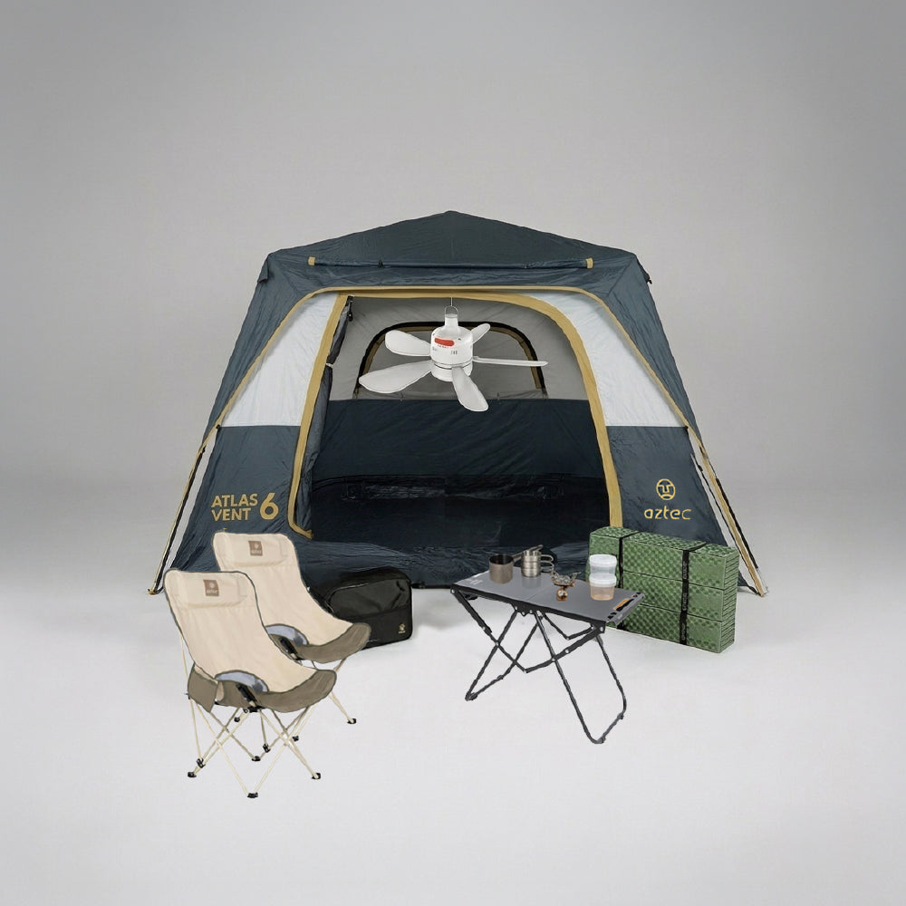 מתקן קמפינג הכולל את האוהל המרווח Aztec Bundle ATLAS VENT 6P בצבעים כחול וצהוב, בליווי שני כיסאות בצבע בז', שולחן מתקפל עם ספלים ותרמוס, קופסה ירוקה, תיק שחור ומאוורר תקרה לבן התלוי בתוך האוהל.